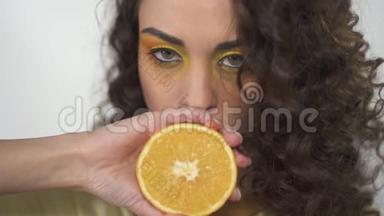 这幅画是一个美丽的女孩抬起眼睛，嘴唇附近拿着一个橘子，挤压着，创造出流动的果汁。 慢慢